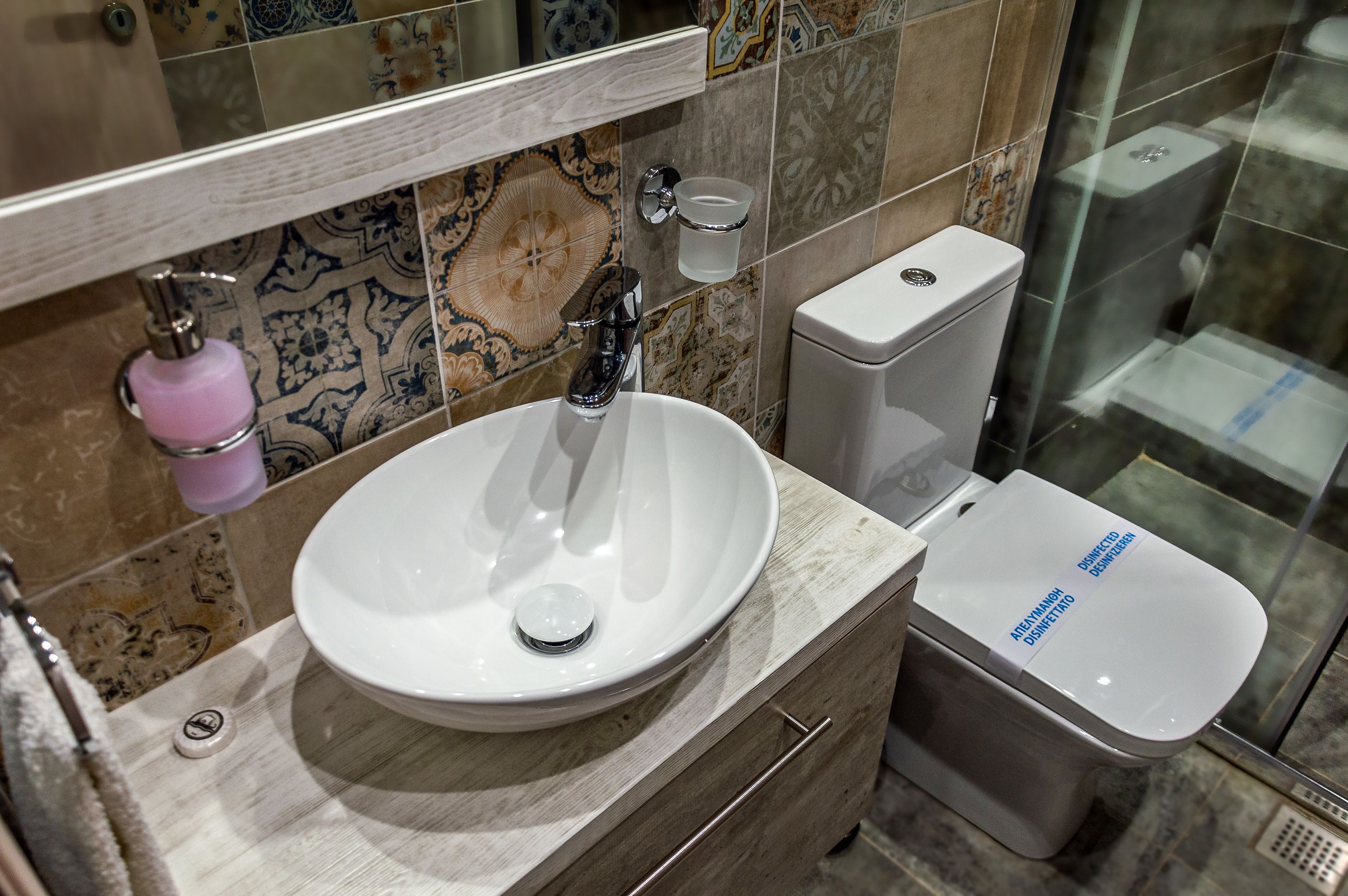 Un baño con un lavabo blanco, un espejo, un inodoro y una zona de ducha.