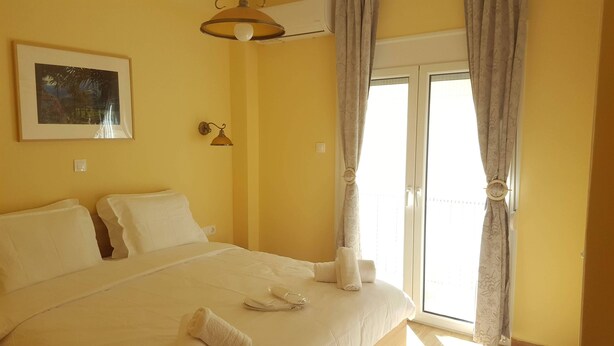 Habitació d'hotel amb un llit, una làmpada penjada a la paret, un quadre i una finestra amb cortines.