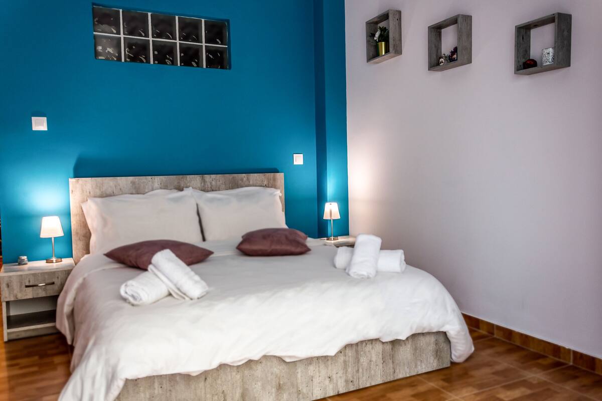 Un dormitorio con una cama grande, dos mesitas de noche y una ventana con vistas.