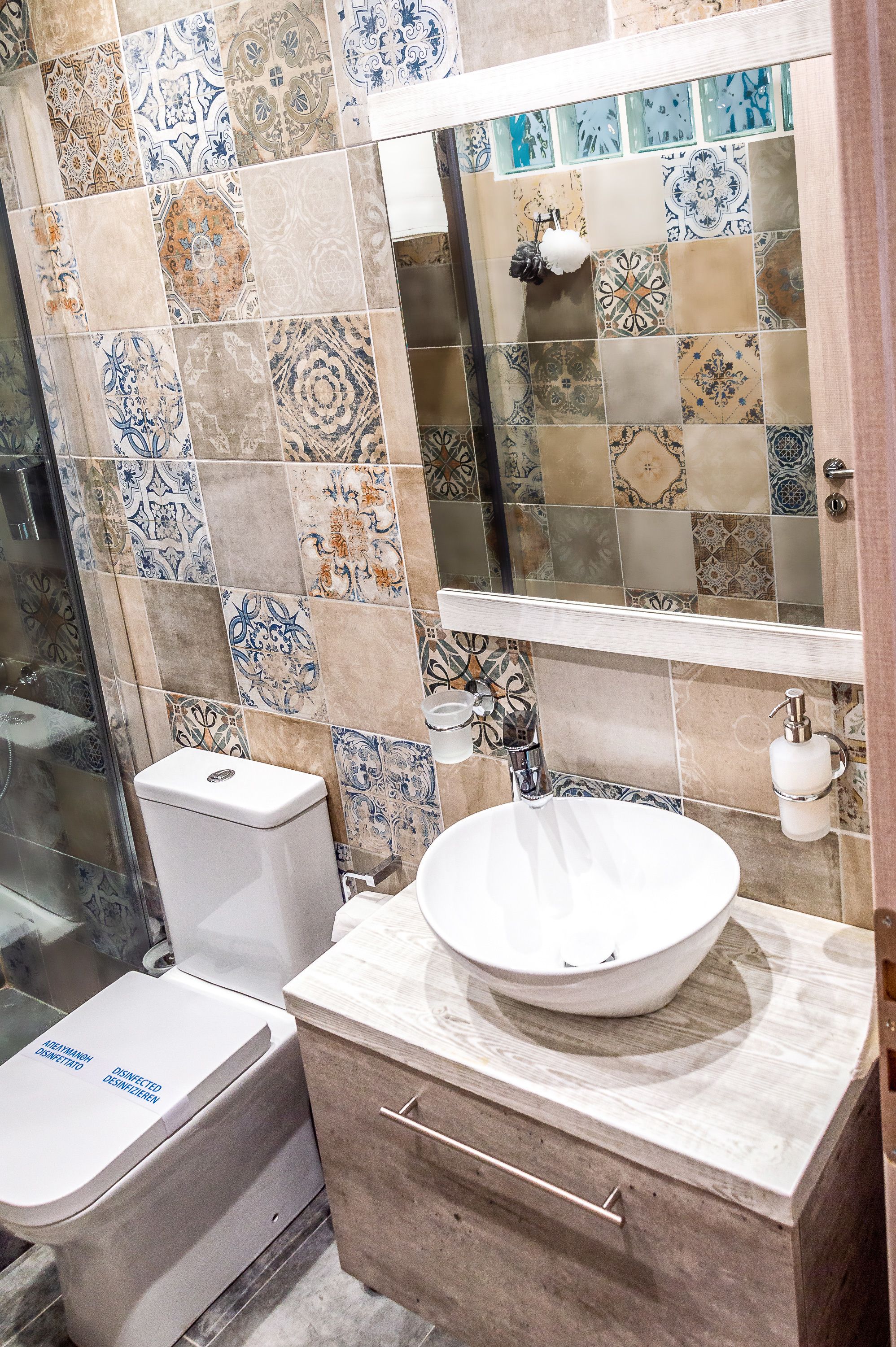 A bathroom with a tiled backsplash, a white sink, and a toilet.