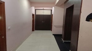 A hallway with a tiled floor, a door at the end, and a light fixture on the ceiling. - ADB Rooms Hotel De Pal Varanasi (Varanasi)