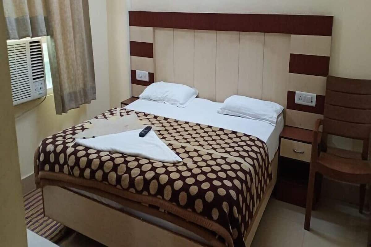 Une chambre d’hôtel comprenant un lit, une table de chevet, une chaise et un appareil de climatisation.