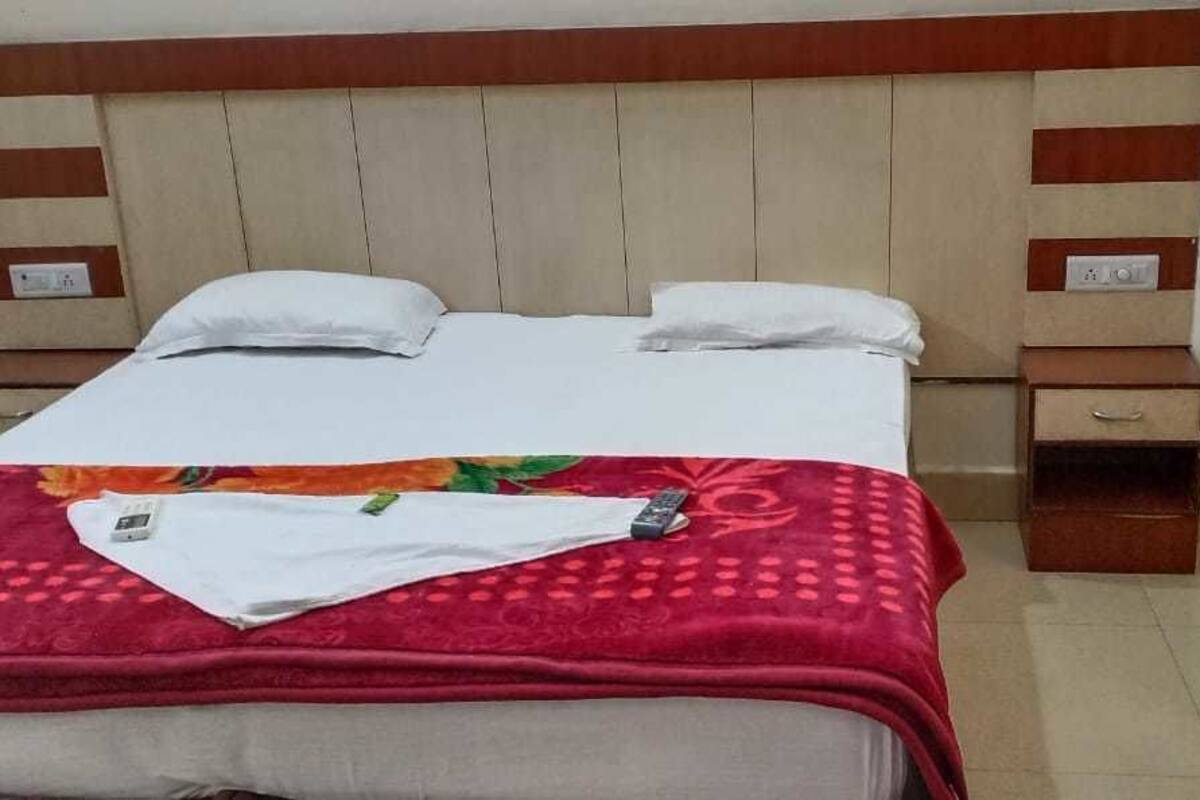 Une chambre d’hôtel avec un lit, deux tables de chevet et une tête de lit en bois.