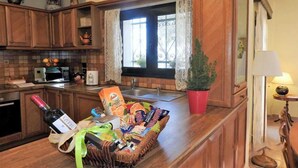 Een keuken met houten kastjes, een magnetron, een spoelbak en een raam met kantgordijnen.
