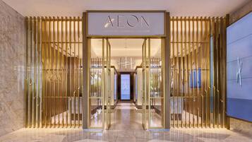 A modern entrance with a glass door, a sign reading 'AEON Centre for Regenerative Wellness,' and a marble floor.