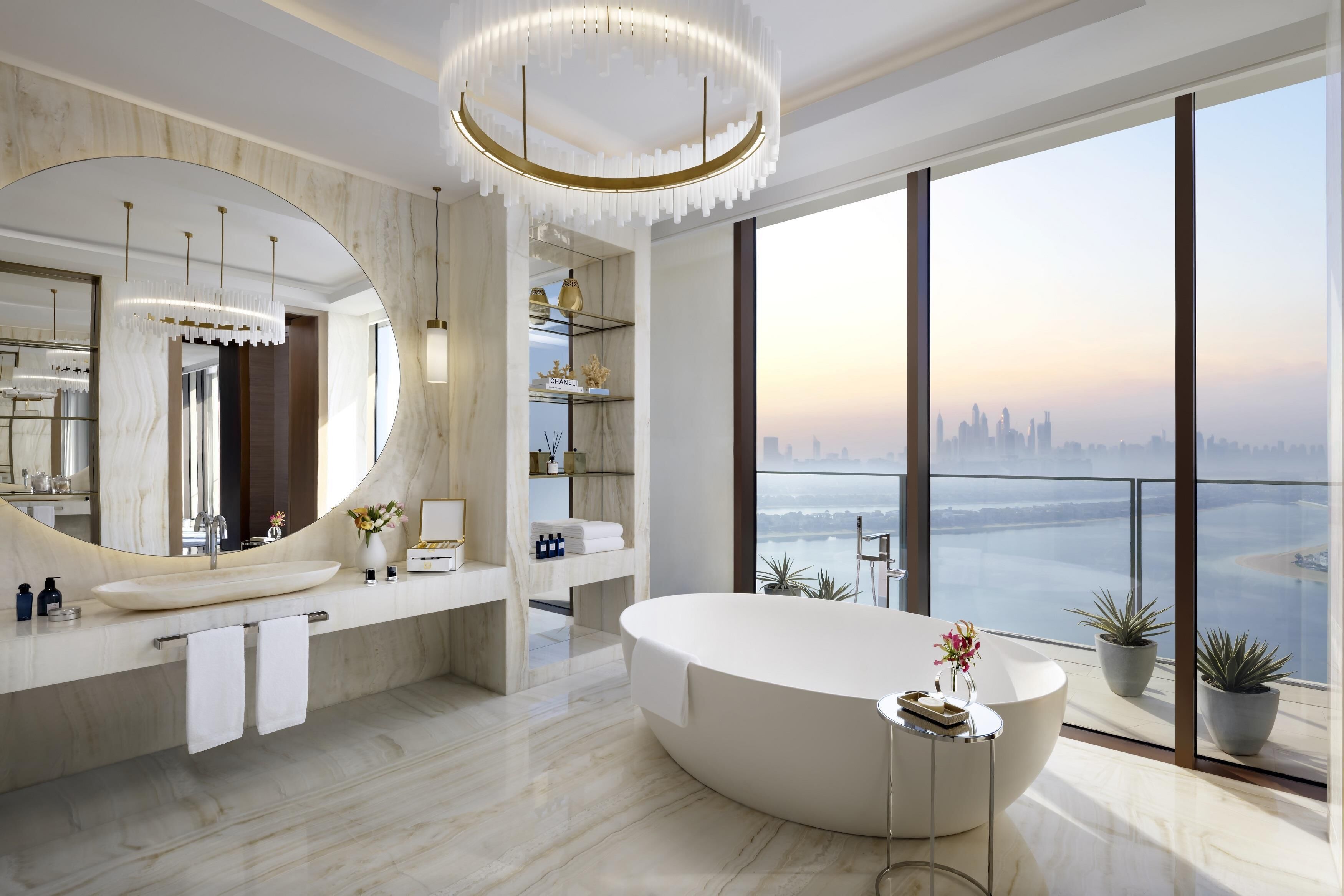 A modern bathroom with a large mirror, a freestanding bathtub, and a view of a city skyline.
