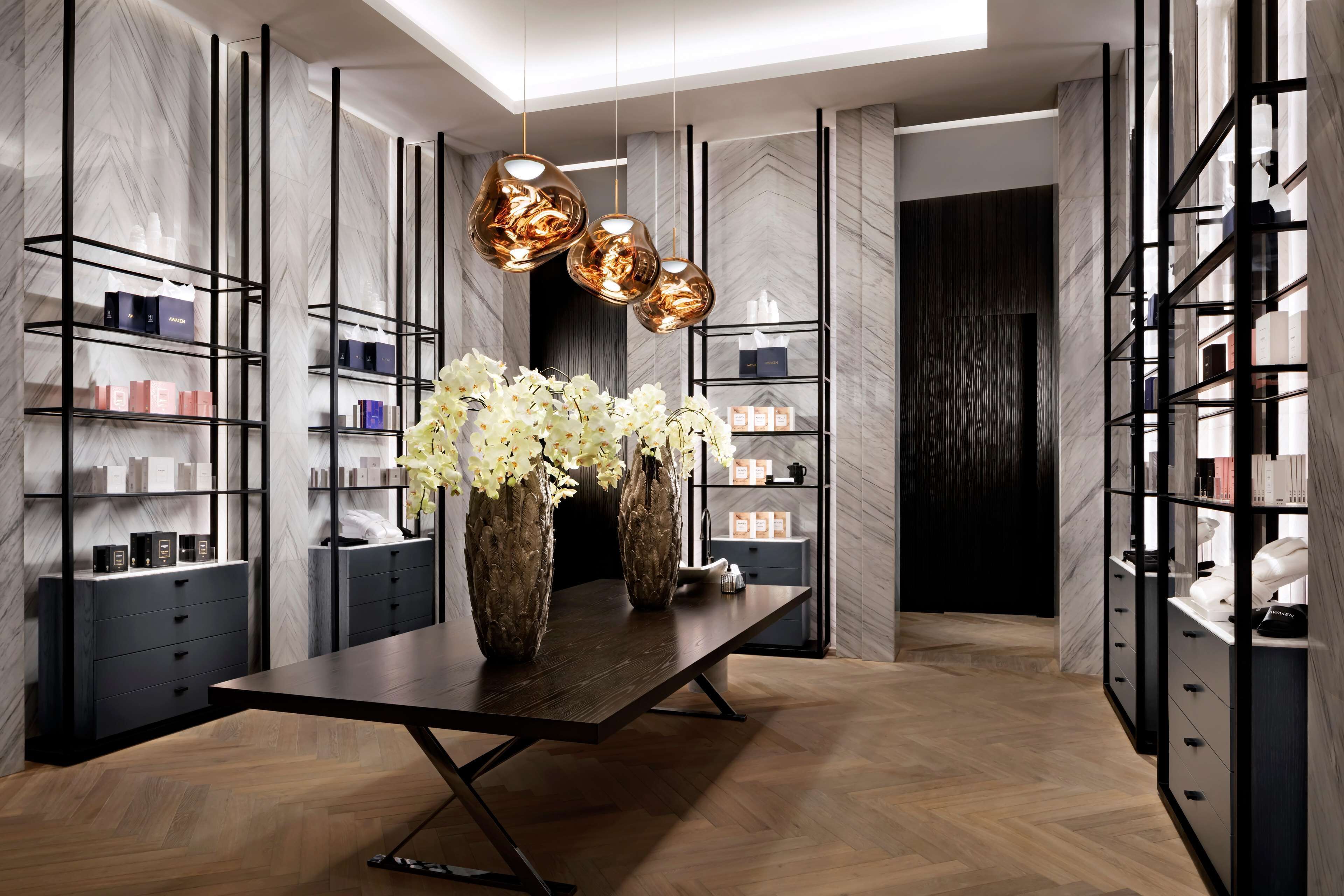 A modern interior with a central table, vases, and shelves with items.