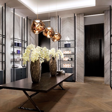 A modern interior with a central table, vases, and shelves with items.