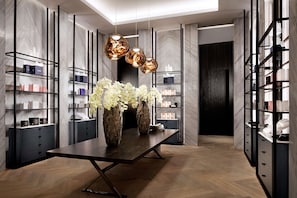 A modern interior with a central table, vases, and shelves with items.
