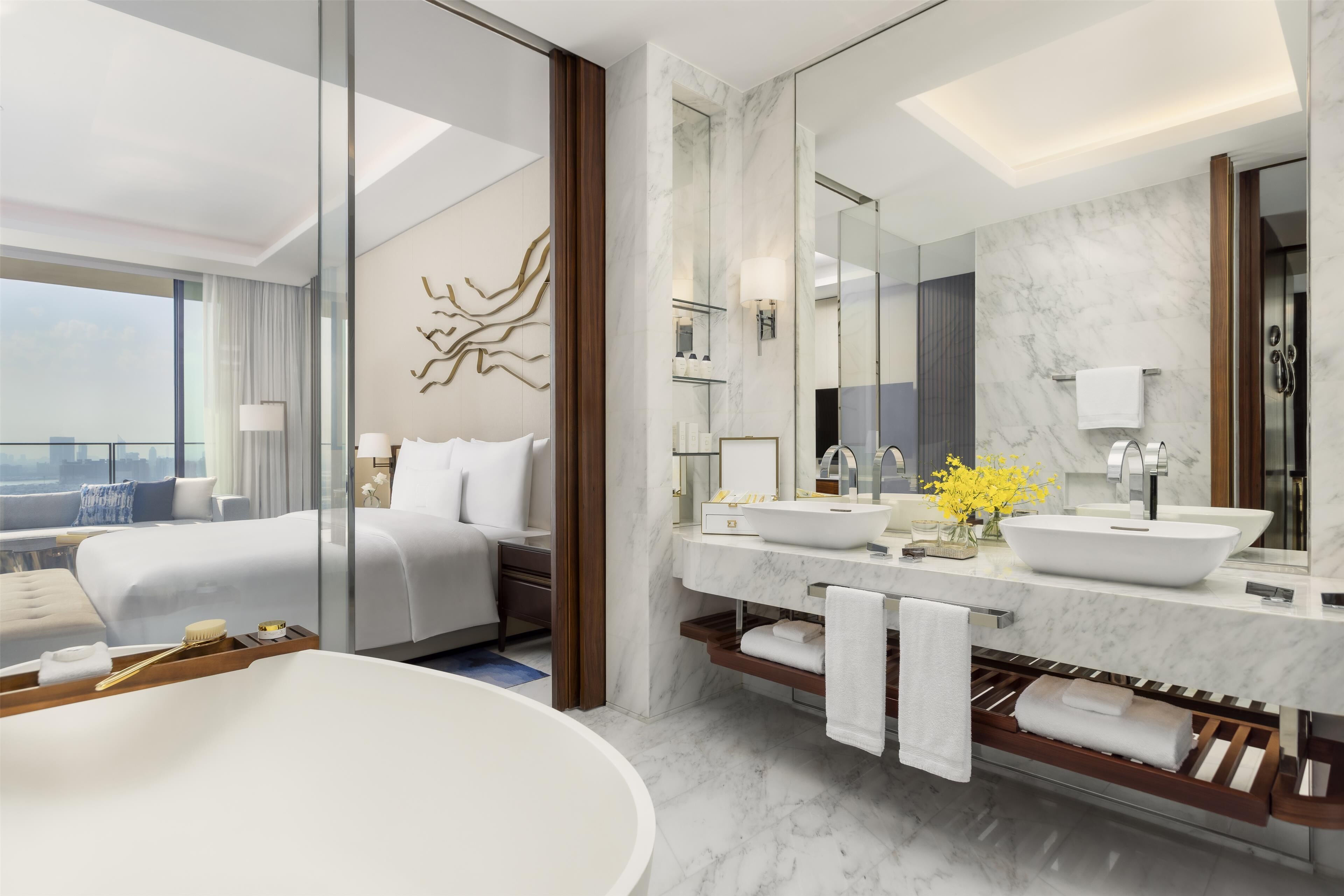 Un bagno moderno con una vasca da bagno ampia, un doppio lavabo con uno specchio grande e un letto con vista sulla città.