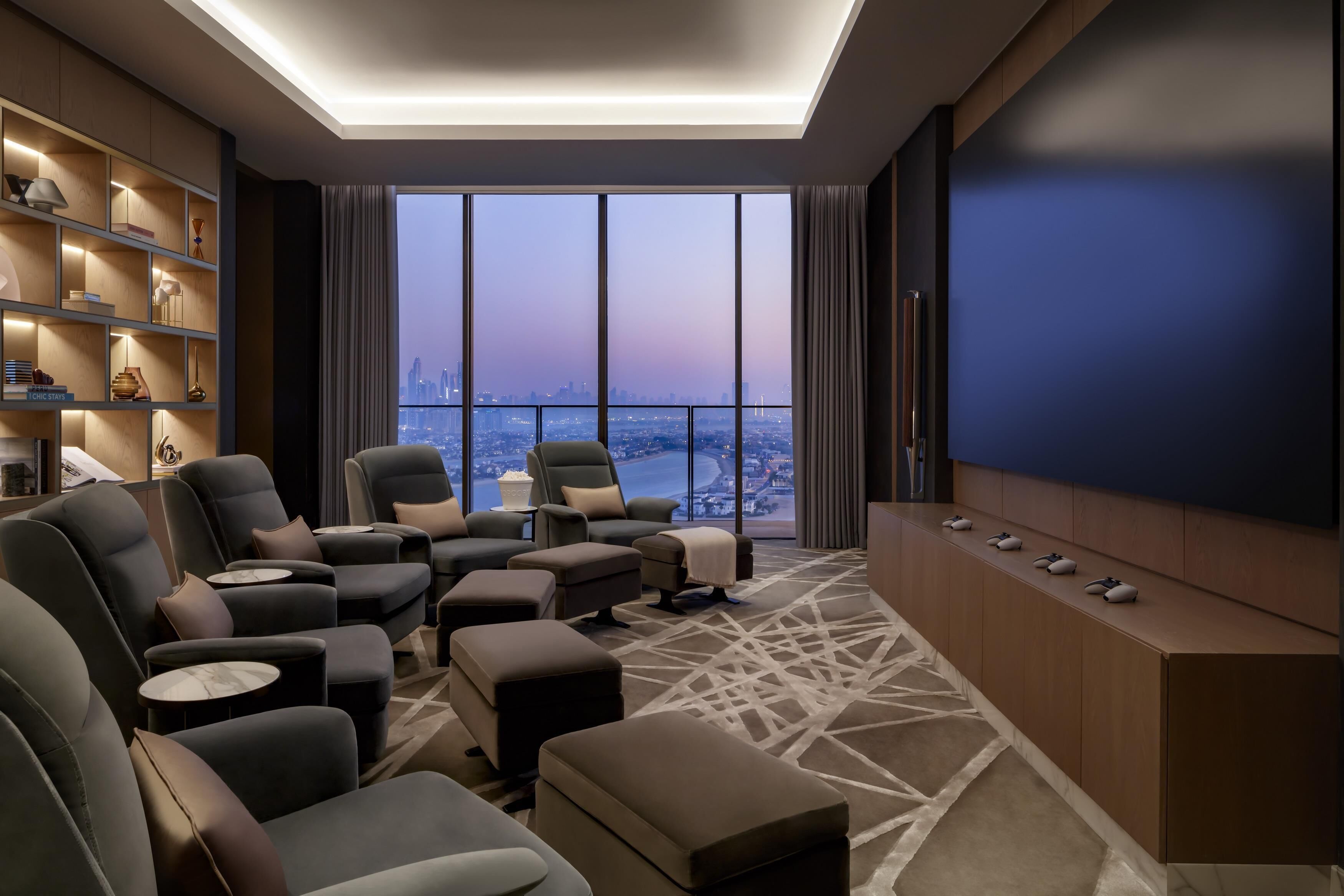 A modern living room with a city view, comfortable seating, a large TV, and a bookshelf.
