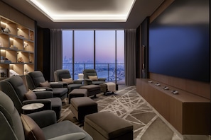 A modern living room with a city view, comfortable seating, a large TV, and a bookshelf.