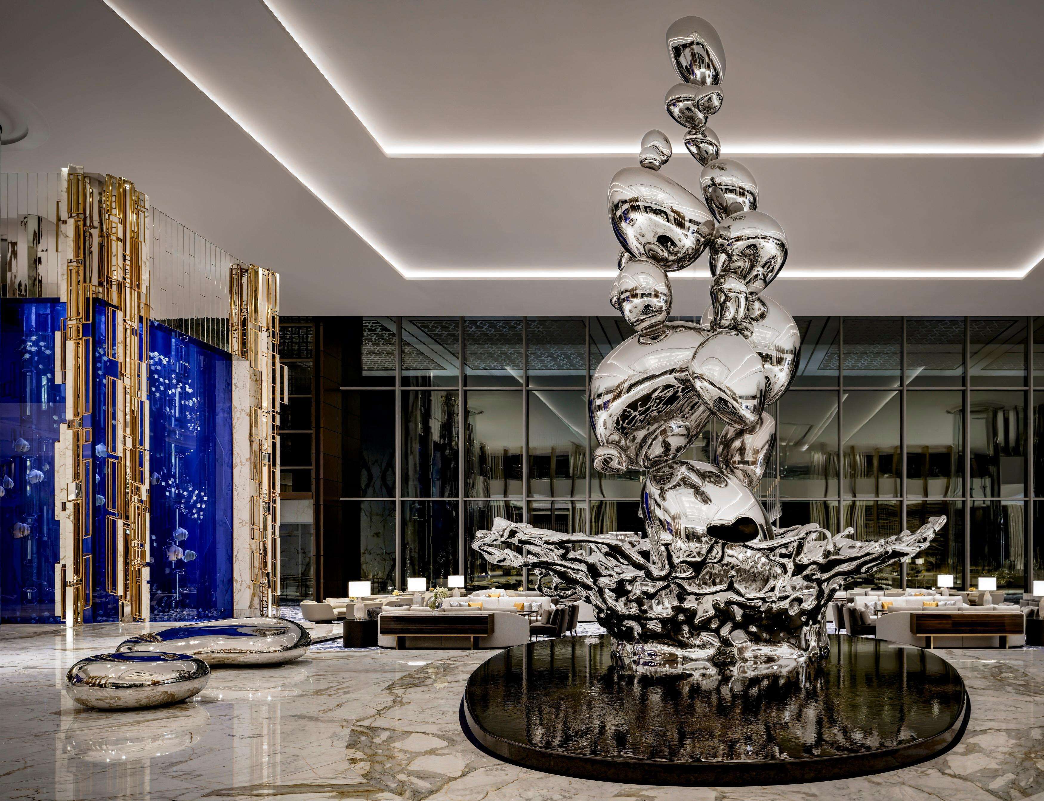 A modern lobby with a central water feature, seating area, and a glass wall.