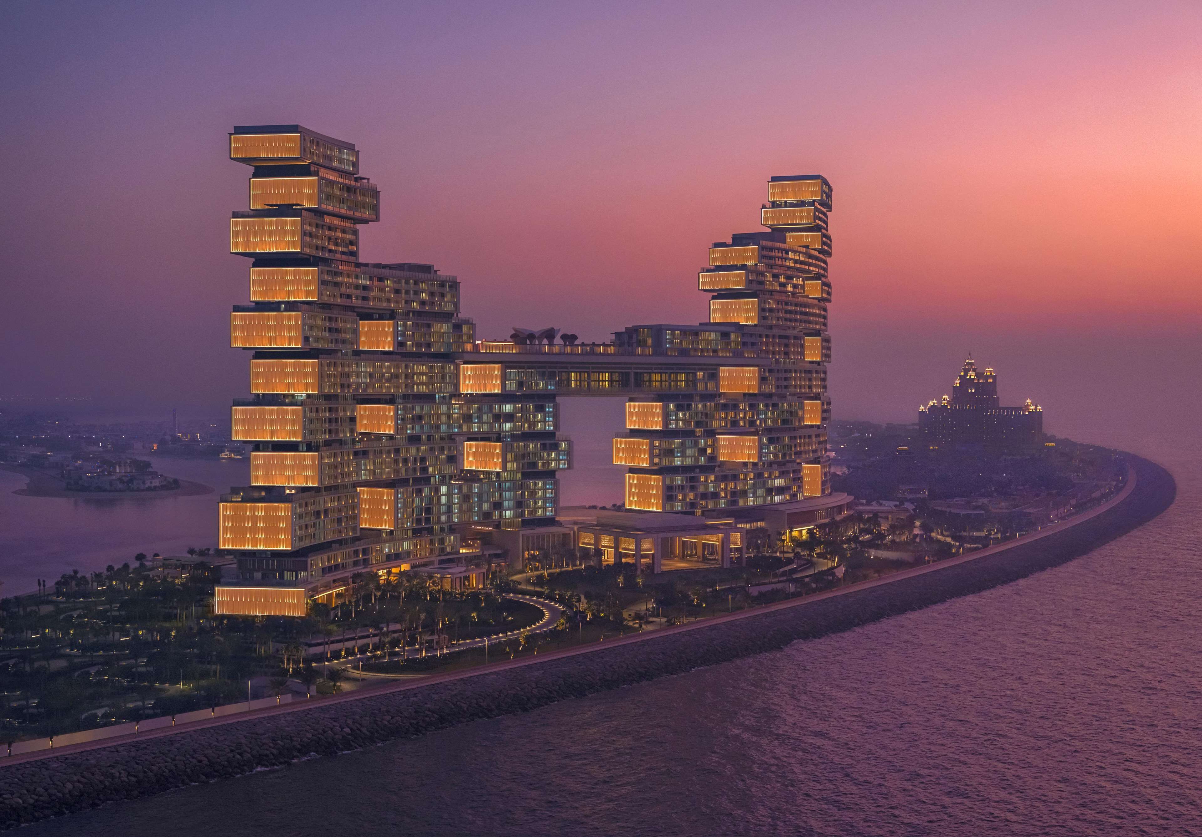 A modern high-rise hotel with multiple balconies, a waterfront view, and a distinctive architectural design.
