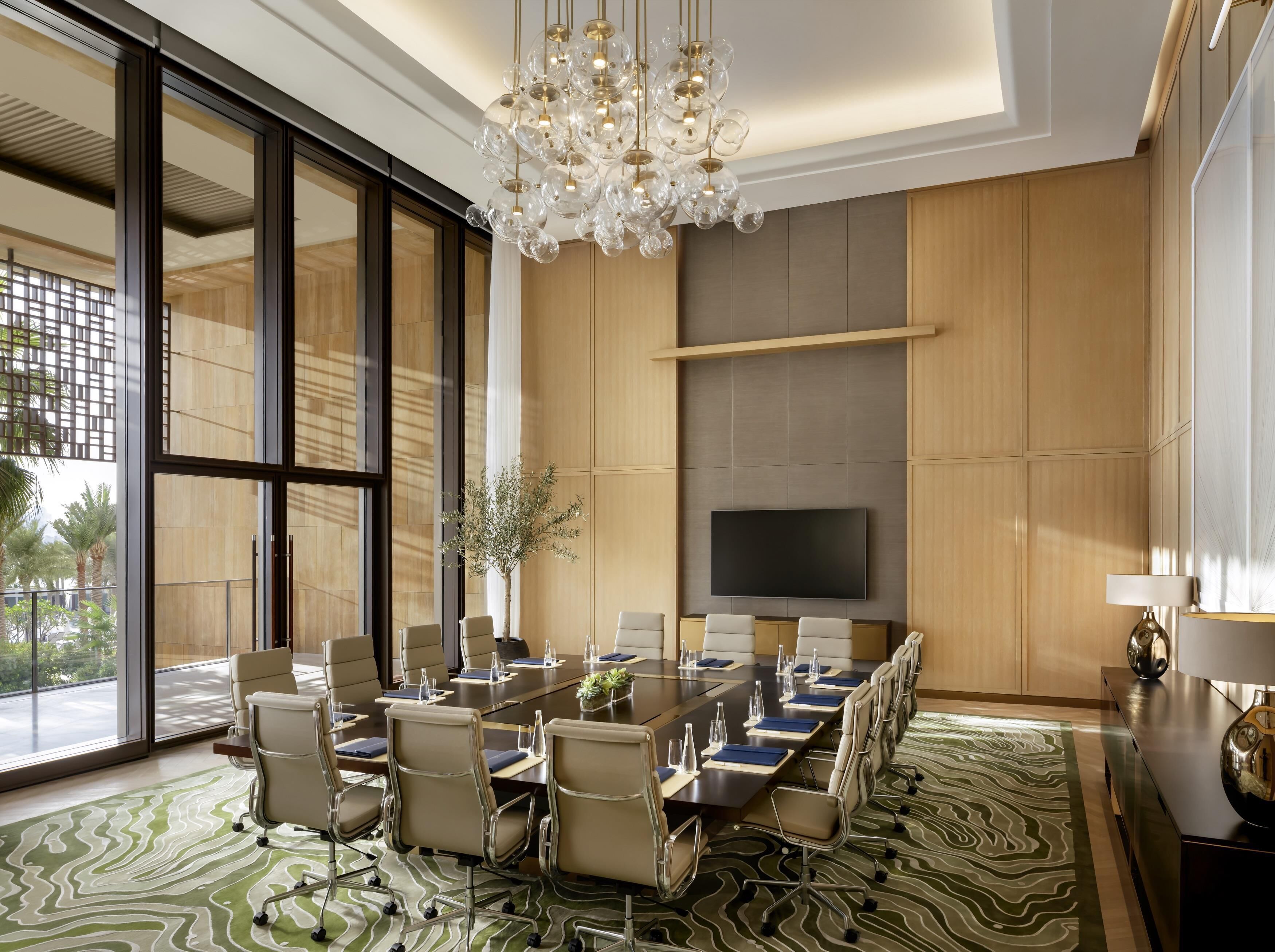 A conference room with a large table, chairs, a television, and a decorative chandelier.