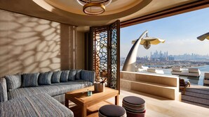 A modern interior with a sofa, table, and ottomans, a decorative partition, and a view of a cityscape.