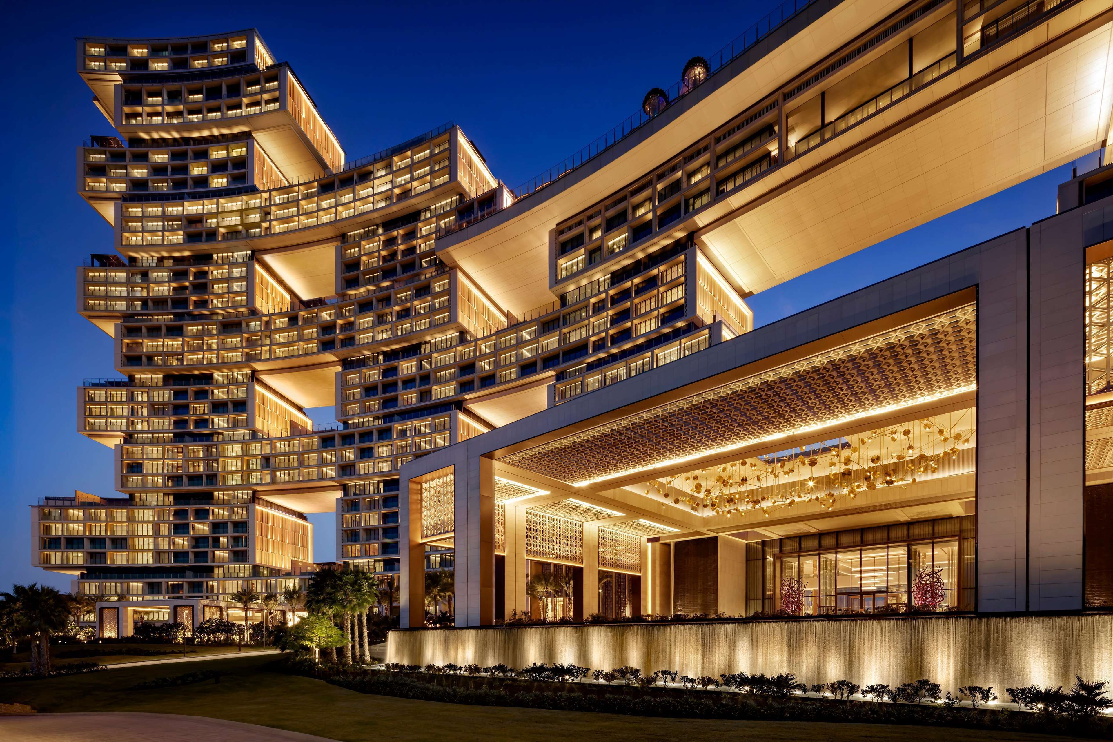 Ein modernes, mehrgeschossiges Hotel mit einzigartigem architektonischen Design, mit Balkonen und einer gut beleuchteten Fassade.