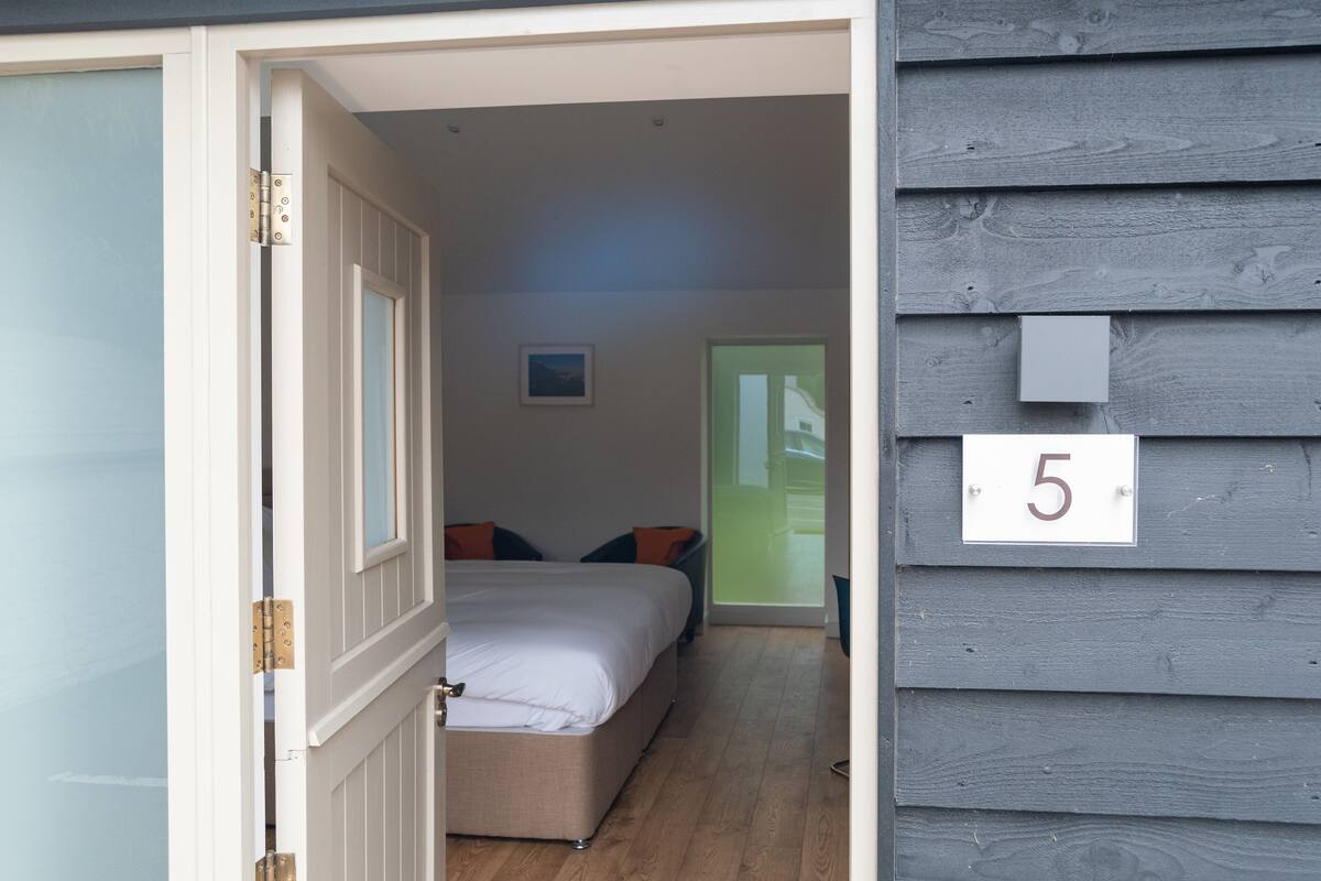 A bedroom with a bed, pillows, a nightstand, and a window.