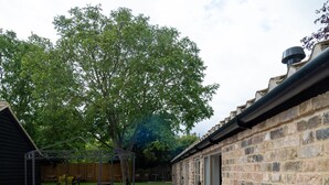 A patio area with outdoor seating, a brick wall, and a wooden fence in the background. - MJP @ The Shepherds (Cambridge)
