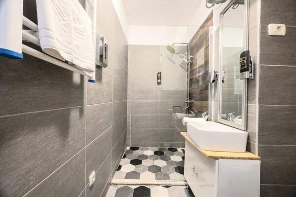 Une salle de bain moderne avec une douche, un lavabo et un miroir.