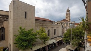 A street view with a historic building, a tower, and a market area.