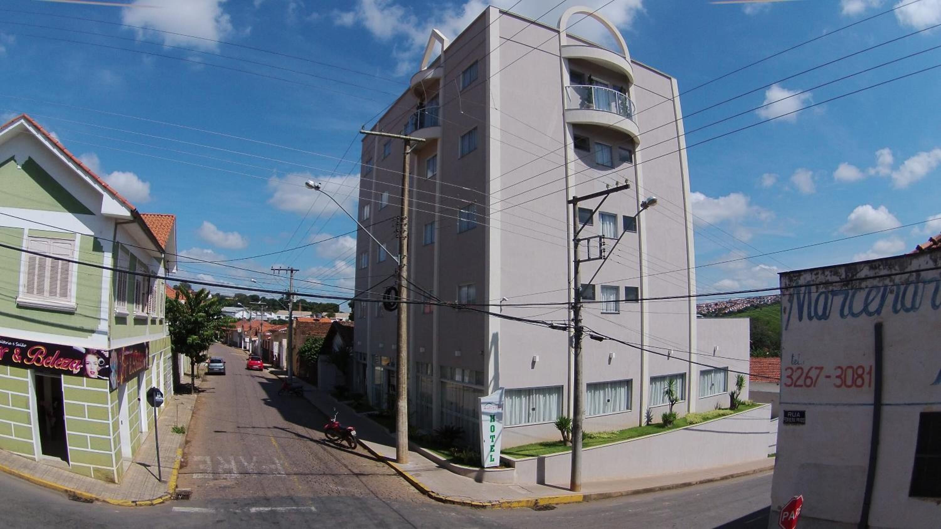 Um hotel moderno com uma torre central, um letreiro visível de um restaurante próximo e uma rua bem visível.