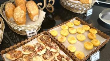 Buffet com diversos itens, incluindo mini pizzas, mini pão de queijo e mais mini pão de queijo.