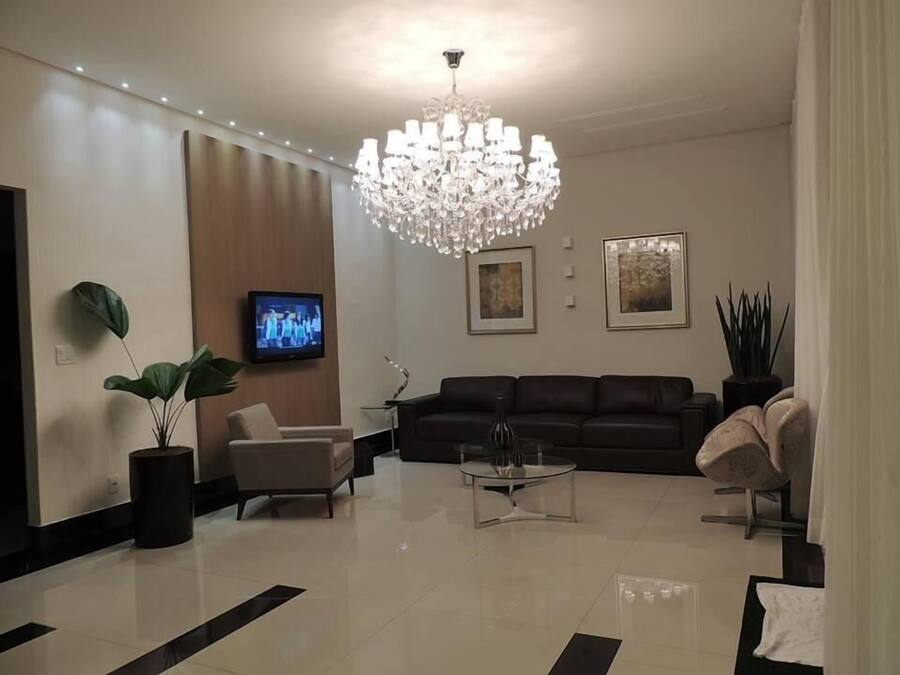 Een moderne woonkamer met een kroonluchter, een televisie, een bank en een salontafel.