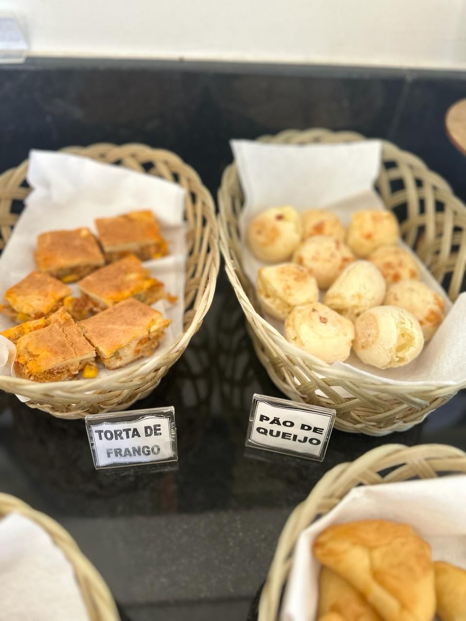 Dos cestas con productos alimenticios, identificados como 'Torta de Frango' y 'Pão de Queijo'.