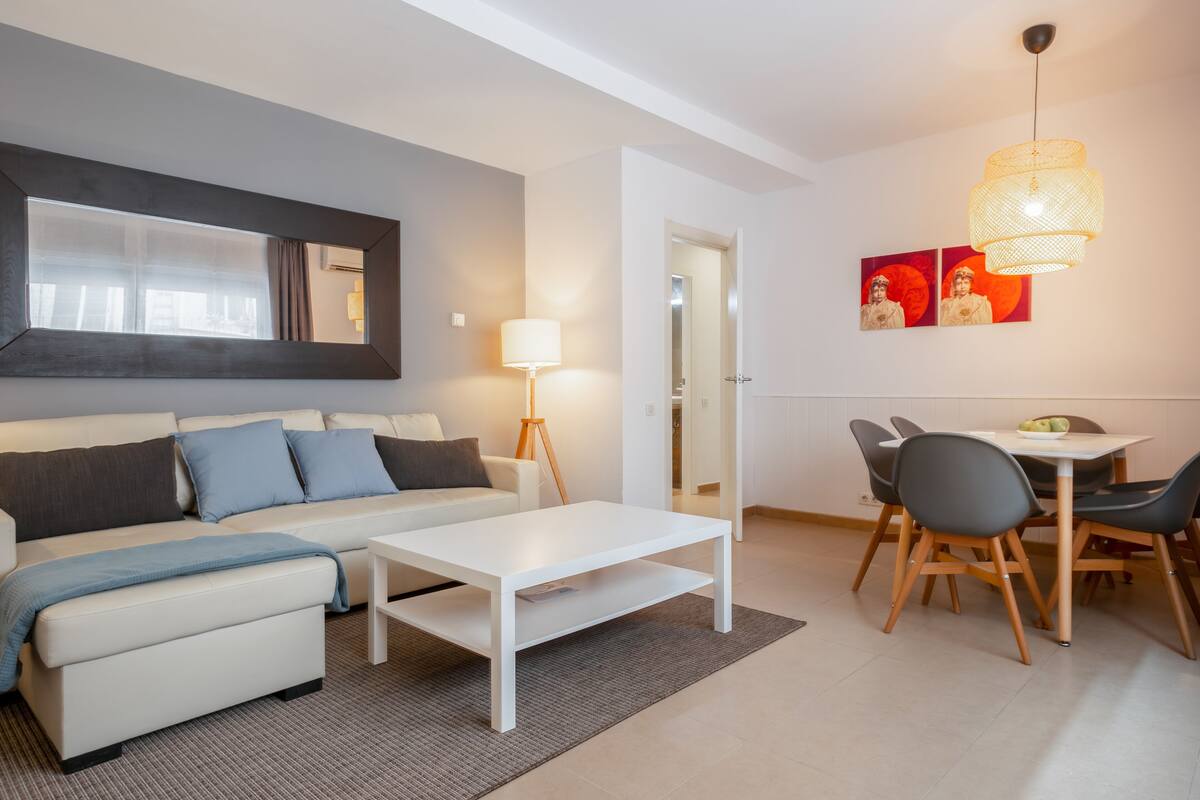 Uma sala de estar moderna com sofá, mesa de centro e área de jantar.