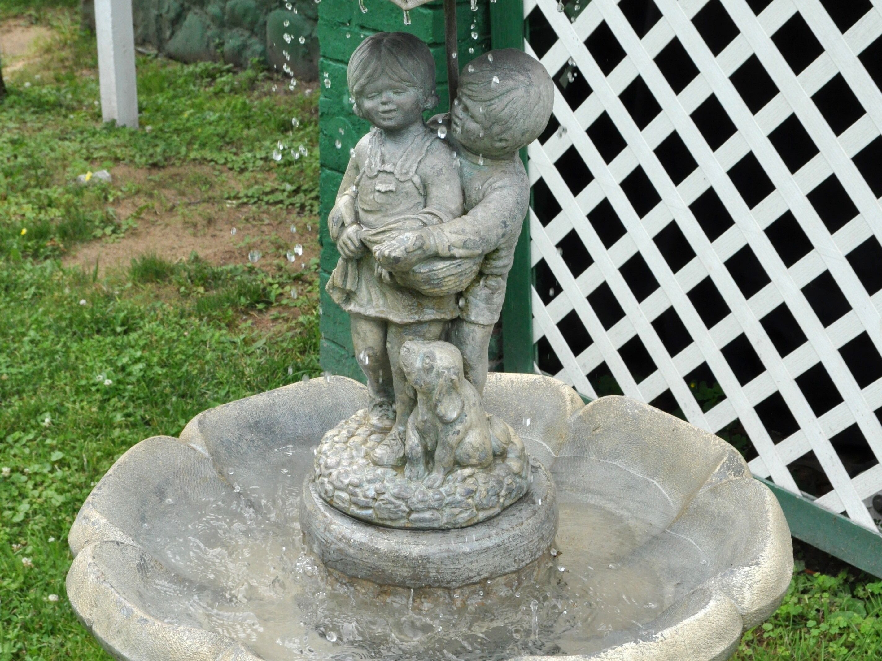 A stone fountain with a statue of two children holding hands, surrounded by water.