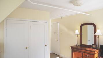 A room with two white doors, a wooden dresser with a mirror, and a ceiling light fixture.