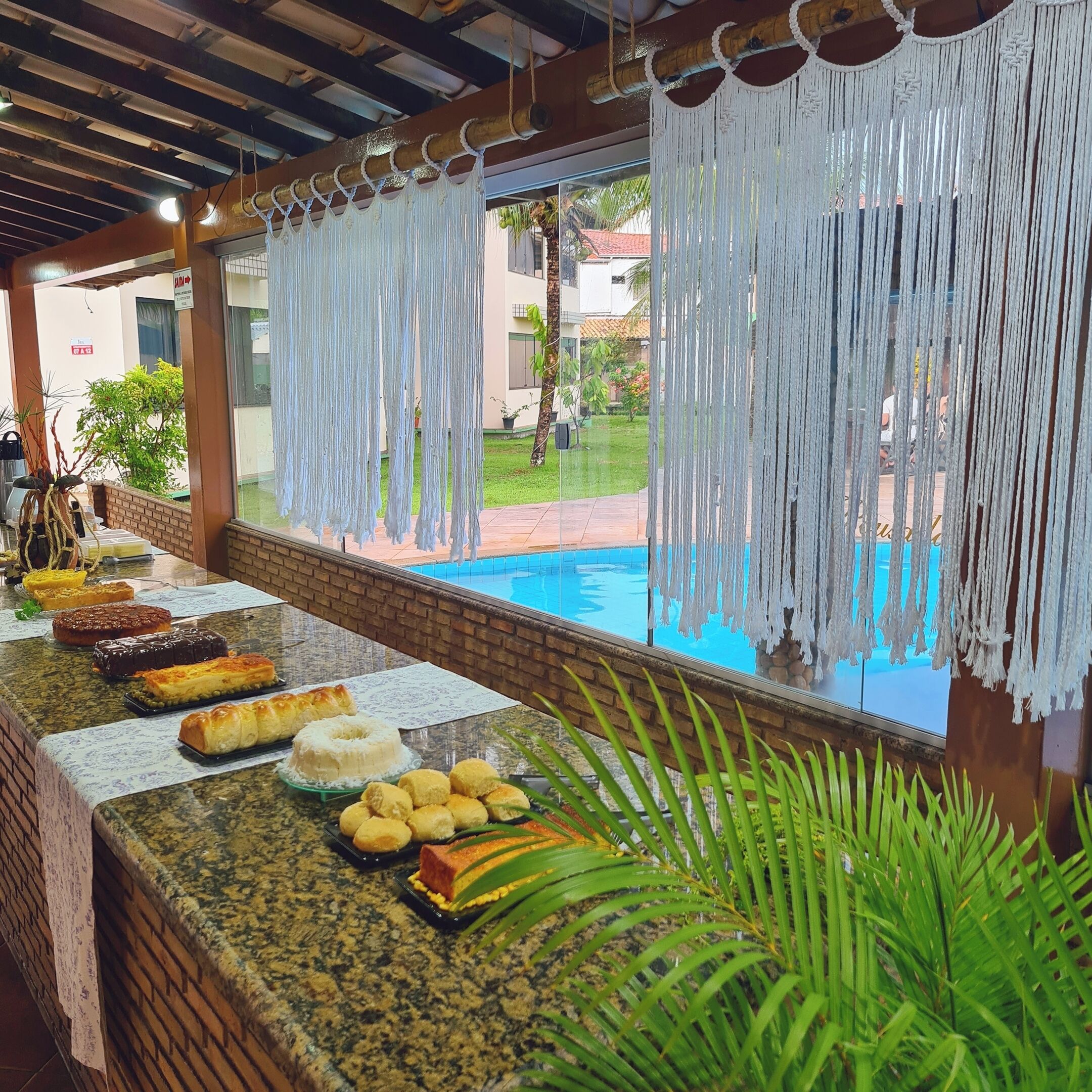 A buffet table with various dishes, a pool in the background, and a view of a residential area.