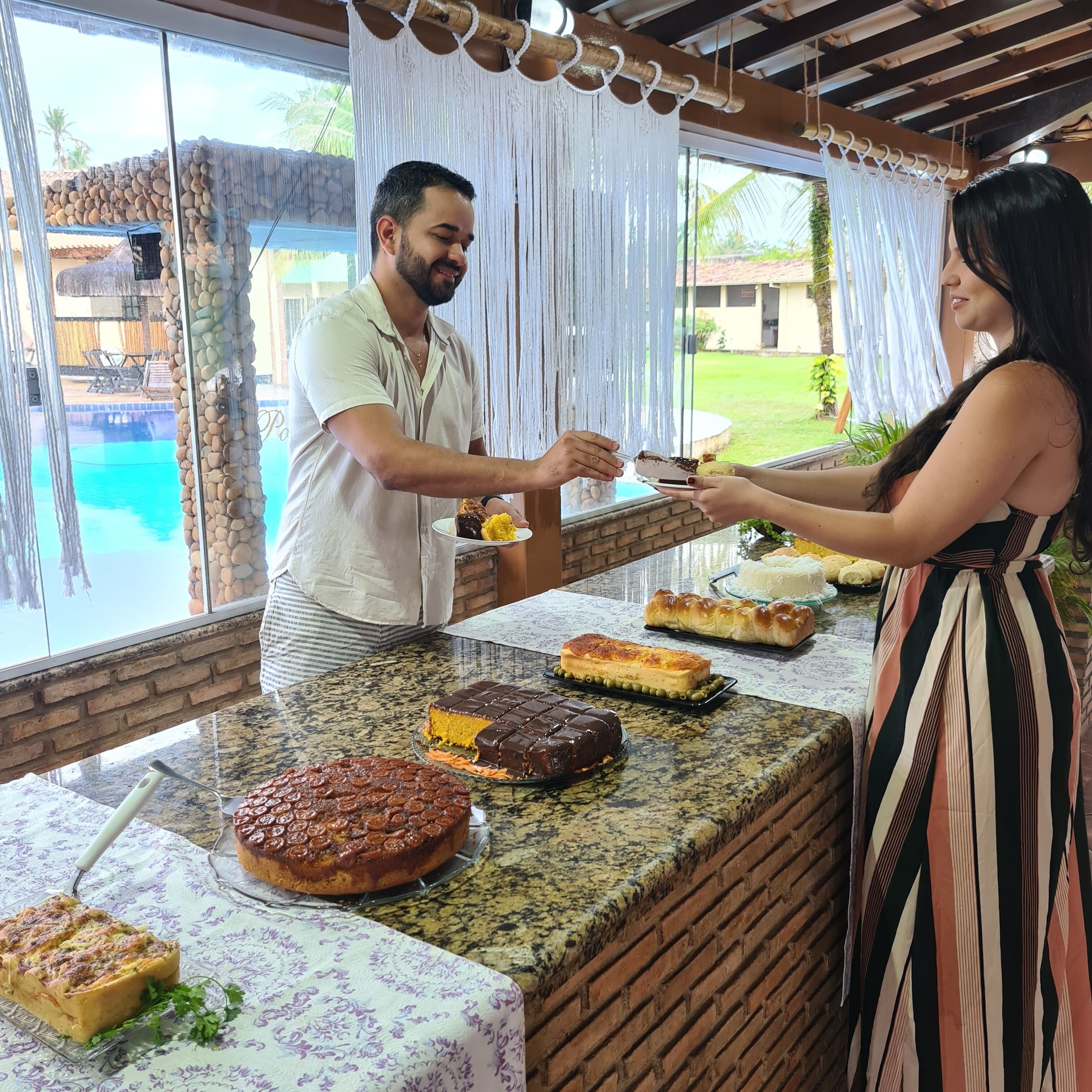 A buffet setup with various desserts and a pool view.