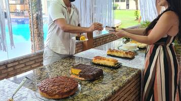 A buffet setup with various desserts and a pool view.
