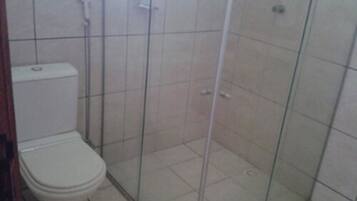 Et badeværelse med toilet, glas brusekabine og fliserede vægge.