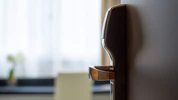 A modern hotel room with a bed, a chair, and a door with a handle.