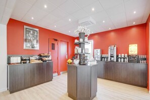 Un'area cucina moderna con isola centrale, mobili in legno e una parete d'accento rossa.