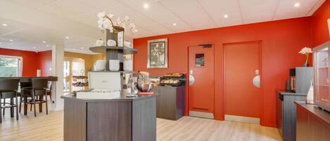 A modern kitchen with a central island, wooden cabinets, and a red accent wall.