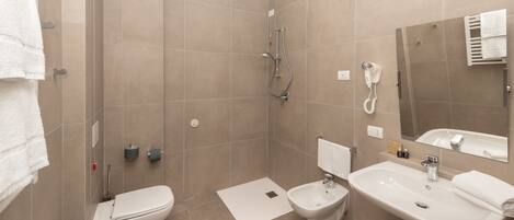 Un baño moderno con ducha, inodoro, bidé y lavamanos.