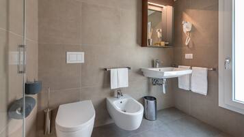 A modern bathroom with a bidet, toilet, sink, and mirror.