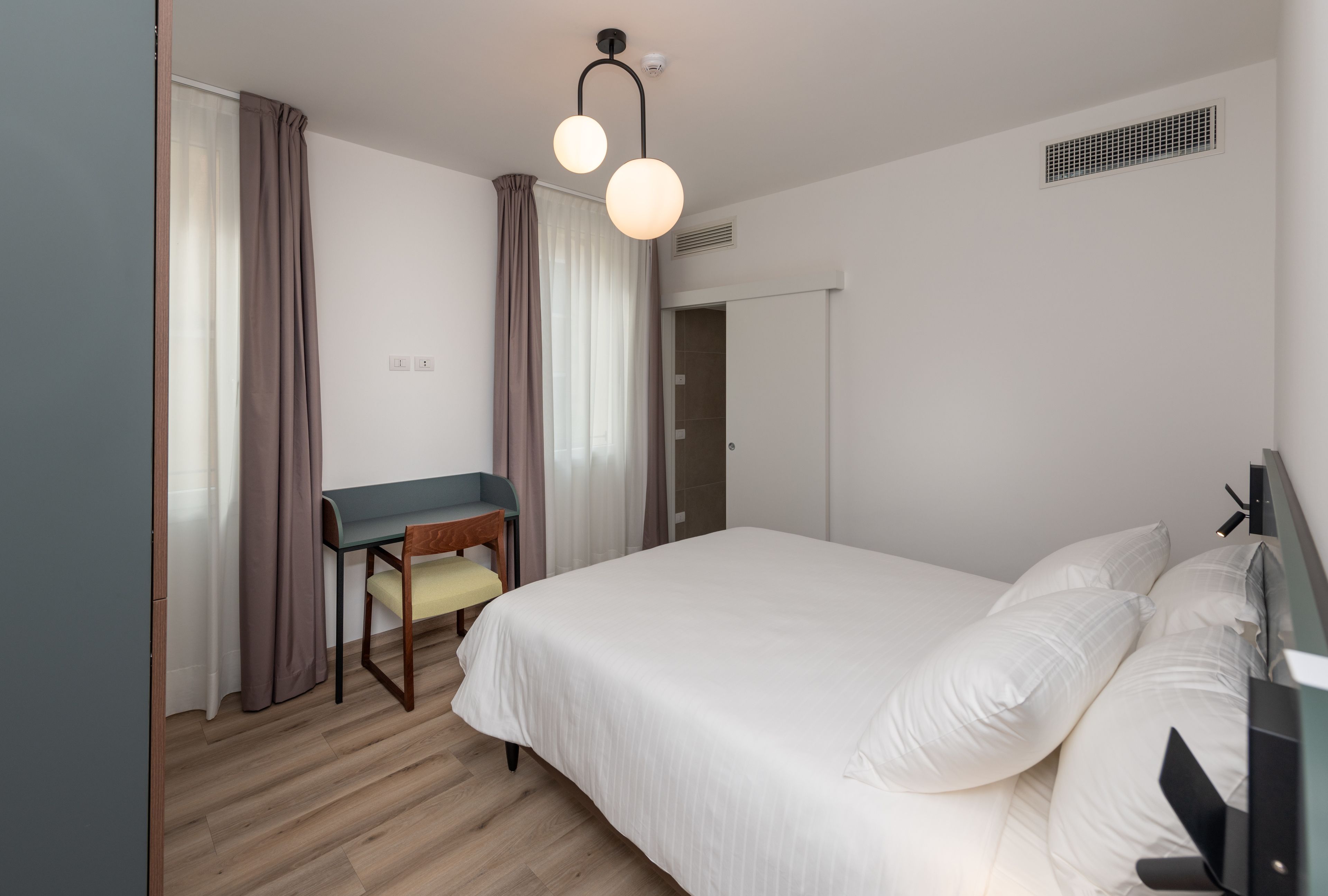 A bedroom with a bed, a desk, and a chair.