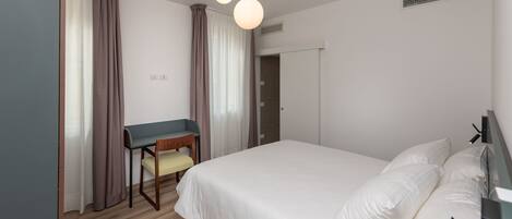 Un dormitorio con una cama, un escritorio y una silla.