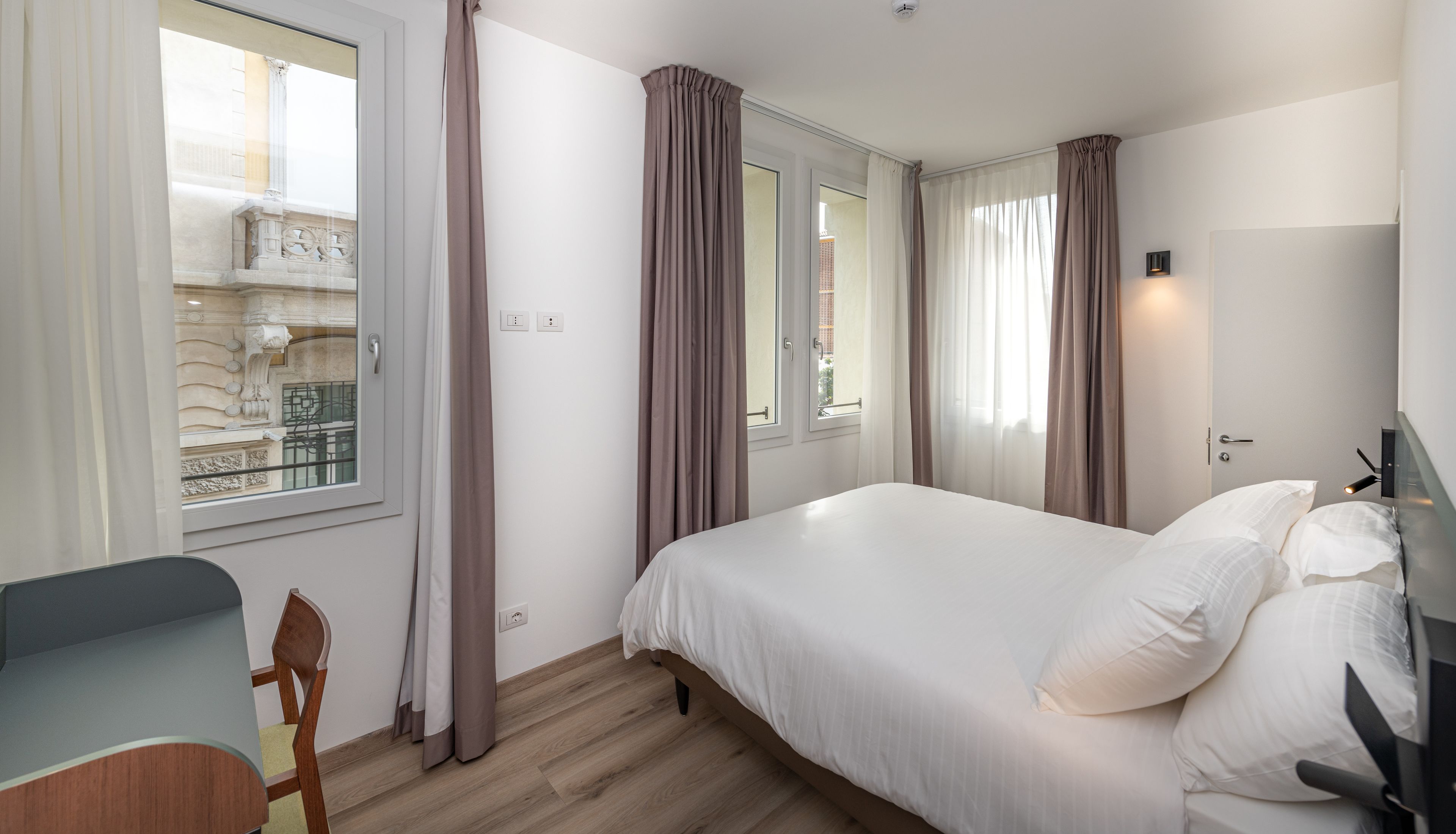 A bedroom with a bed, a desk, and a chair.