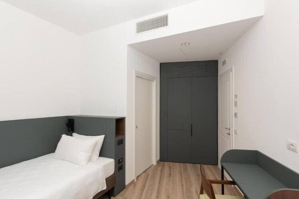 Un dormitorio pequeño y moderno con una cama individual, un escritorio y un armario.