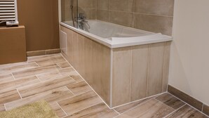 A modern bathroom with a freestanding bathtub, wooden flooring, and beige tiles. - La ferme saint Jacques (Chatellerault)