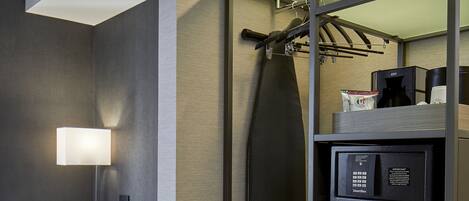 A modern hotel room with a desk, chair, and a built-in wardrobe with a hanging rack.