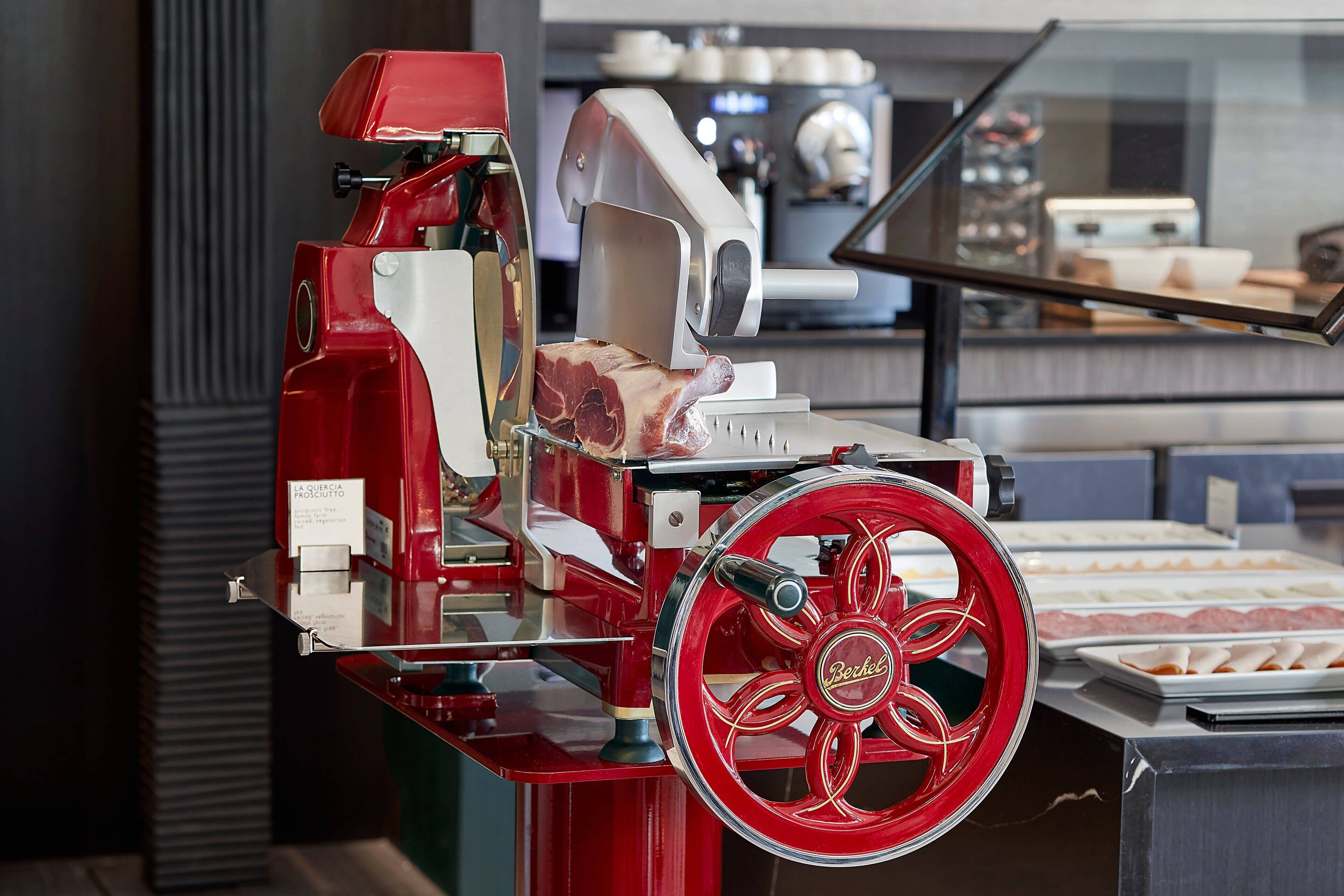 A meat carving station with a red wheel and a display of sliced meats.