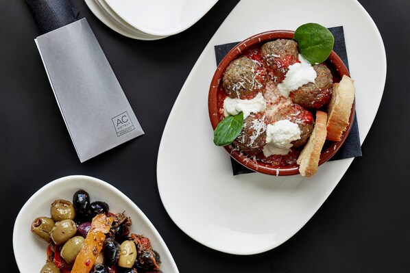 A dining table with a plate of meatballs, a bowl of olives, and a napkin. - AC Hotel Miami Wynwood (Miami)