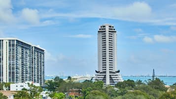 A high-rise building with a modern architectural design, surrounded by lush greenery and a clear blue sky.